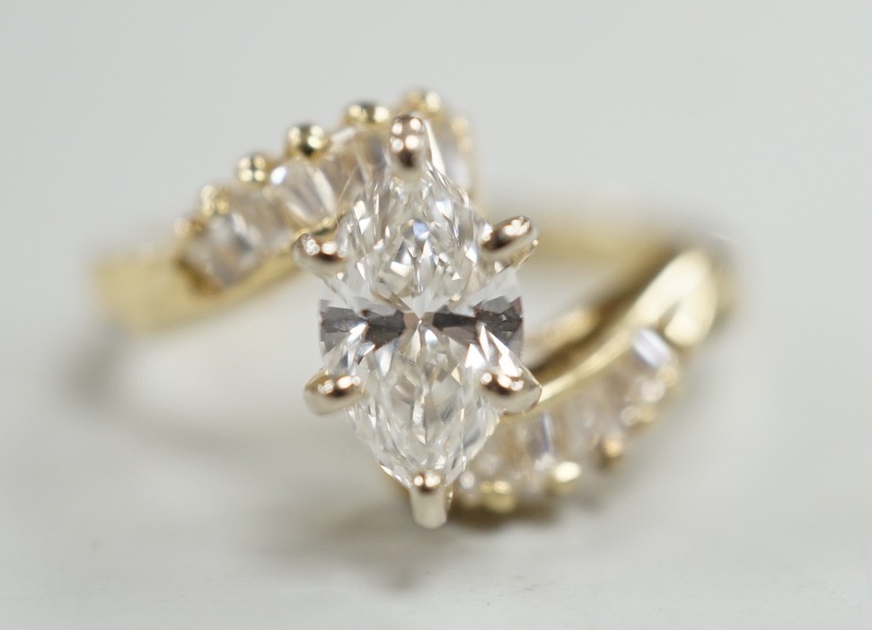 A yellow metal and singe stone marquise cut diamond set crossover dress ring, with baguette cut diamond set shoulders, size J/K, gross weight 3.2 grams.